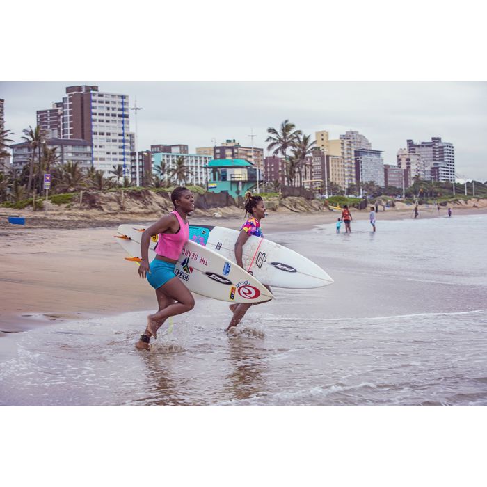 Coastal beachDurbanTwo women running into the sea with surfboards